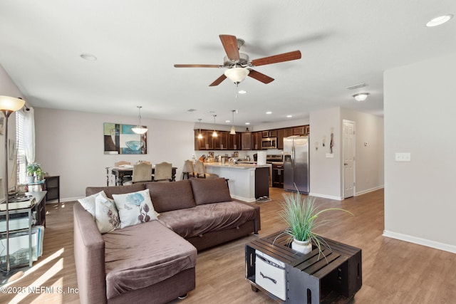 living area with baseboards, visible vents, and light wood finished floors