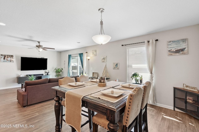 dining space with light wood-type flooring, baseboards, and a ceiling fan