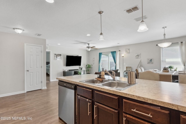 kitchen featuring open floor plan, dark brown cabinets, stainless steel dishwasher, and a sink