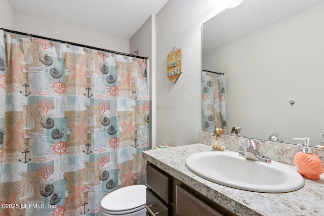 full bathroom featuring a textured wall, vanity, and toilet