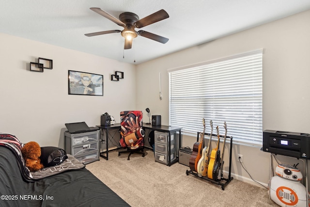 carpeted office space with a ceiling fan and baseboards