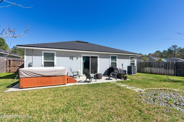 back of house with a hot tub, a lawn, a patio, a fenced backyard, and stucco siding