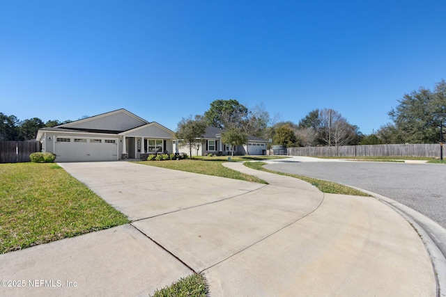 view of front facade with driveway, an attached garage, fence, and a front yard