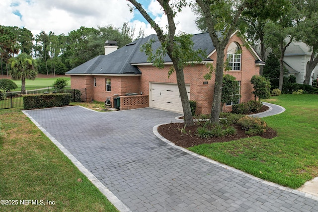 view of side of home featuring decorative driveway, fence, a yard, brick siding, and a chimney