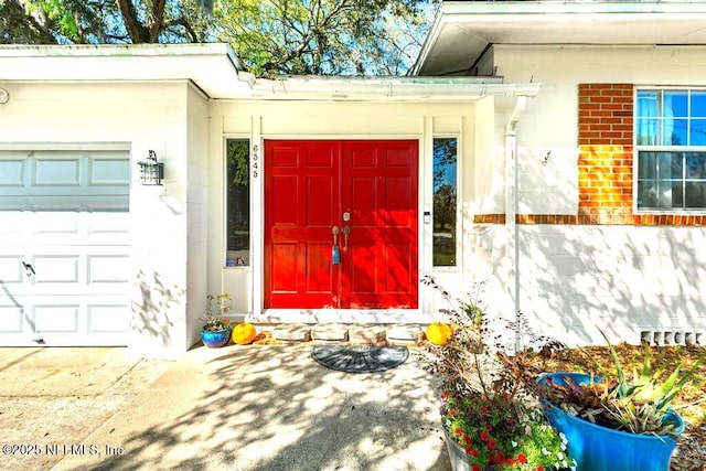 view of exterior entry with a garage and brick siding