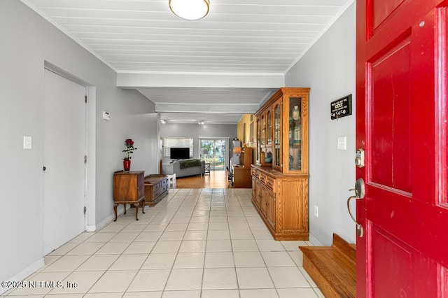 entrance foyer with light tile patterned floors, beam ceiling, and baseboards