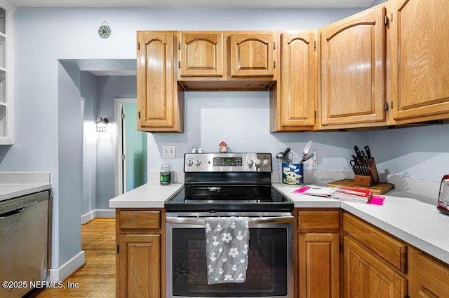 kitchen with light wood finished floors, appliances with stainless steel finishes, and light countertops