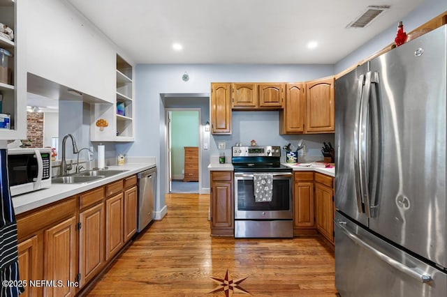 kitchen featuring visible vents, open shelves, a sink, light countertops, and appliances with stainless steel finishes