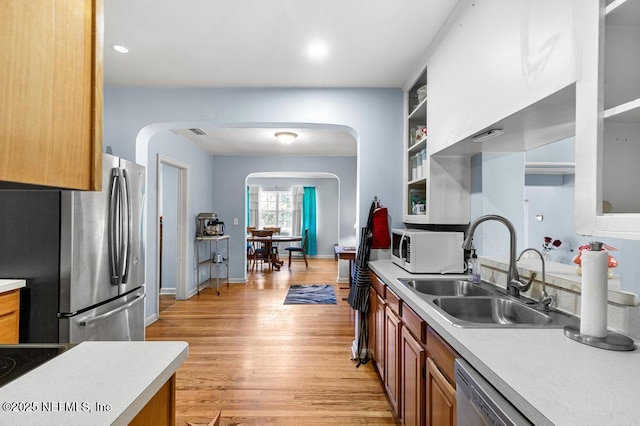 kitchen with light countertops, arched walkways, appliances with stainless steel finishes, and a sink