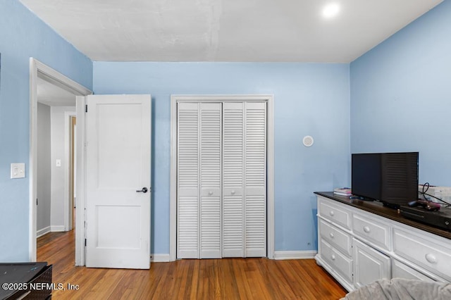 bedroom with wood finished floors, a closet, and baseboards