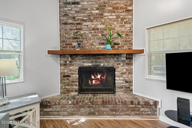 room details featuring a brick fireplace, wood finished floors, and baseboards