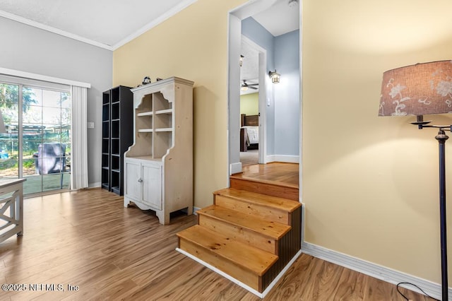 stairs featuring ornamental molding, baseboards, and wood finished floors