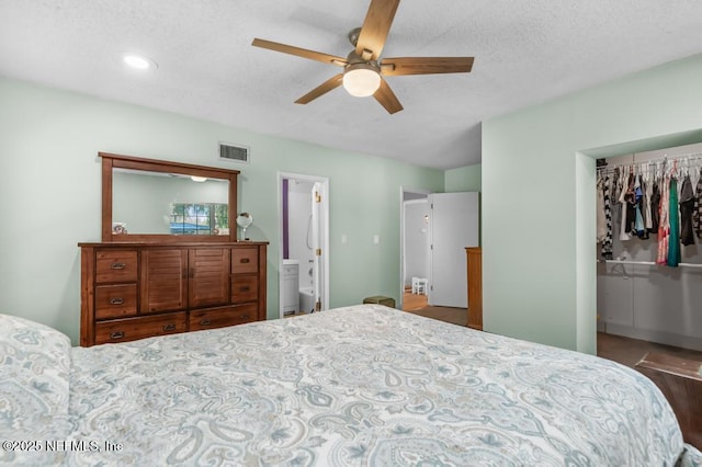 bedroom featuring visible vents, ceiling fan, a spacious closet, a textured ceiling, and connected bathroom