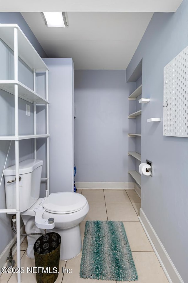 bathroom featuring baseboards, toilet, and tile patterned flooring