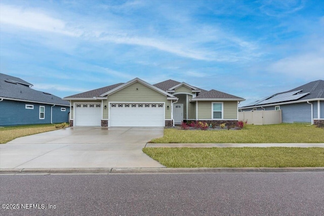 view of front of house featuring concrete driveway, a front yard, fence, a garage, and stone siding