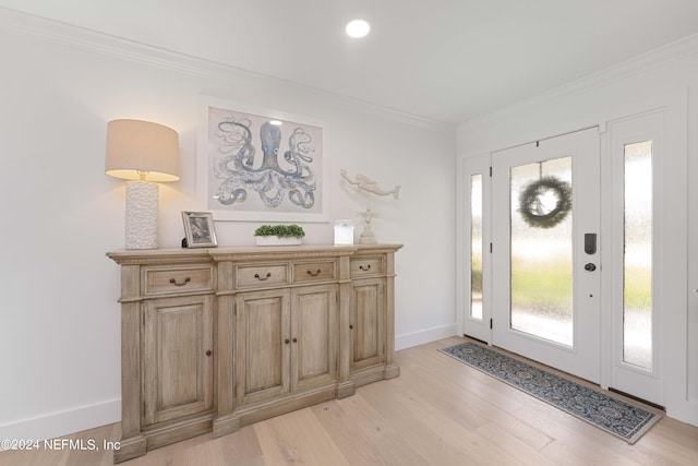 entryway with ornamental molding, light wood-type flooring, and baseboards