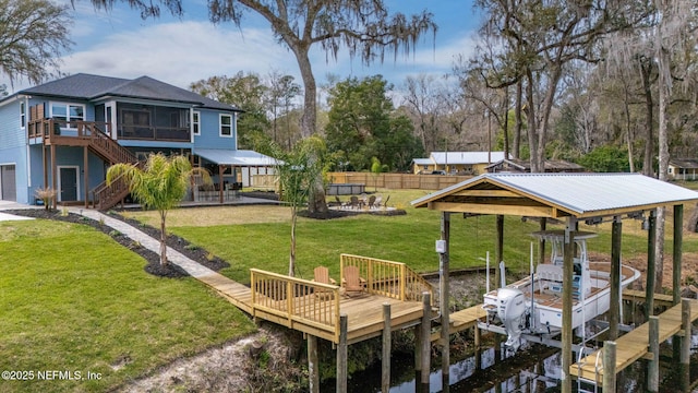 dock area with a yard, stairway, boat lift, and fence