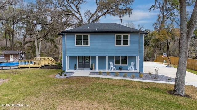 back of property with covered porch, a yard, and fence