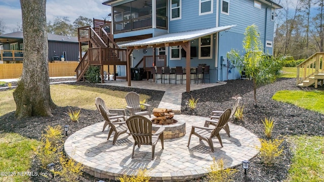 back of property with an outdoor fire pit, a sunroom, a patio area, and stairs