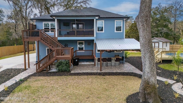 back of property featuring a deck, a patio, an outdoor structure, fence, and a storage unit