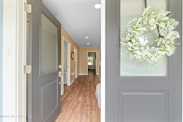 doorway with light wood-type flooring, baseboards, and recessed lighting