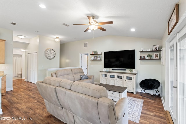 living room featuring lofted ceiling, dark wood-style flooring, and visible vents