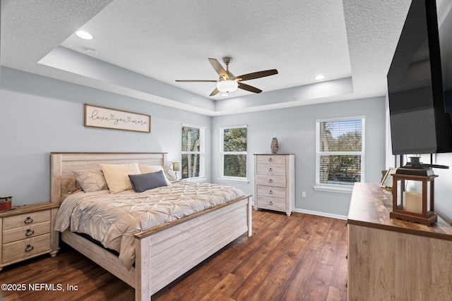 bedroom featuring a textured ceiling, a tray ceiling, and dark wood finished floors