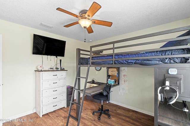 bedroom featuring a textured ceiling, wood finished floors, visible vents, and baseboards