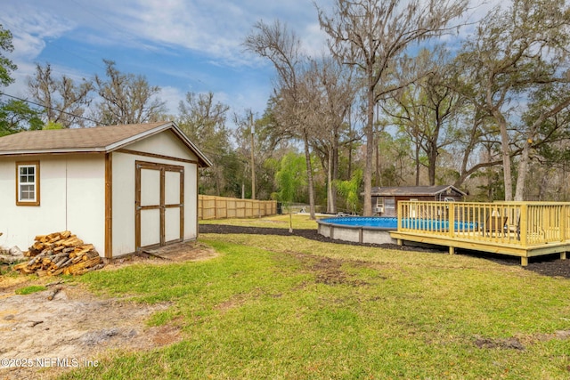 view of yard with a fenced in pool, an outbuilding, a storage shed, fence, and a deck