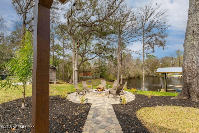 view of yard with a fire pit, a patio, a dock, and a water view