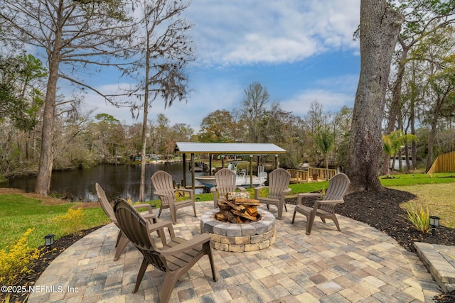 view of patio / terrace featuring an outdoor fire pit, a water view, and fence