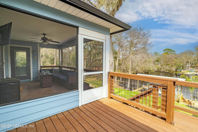 wooden deck featuring a water view, a sunroom, and a ceiling fan