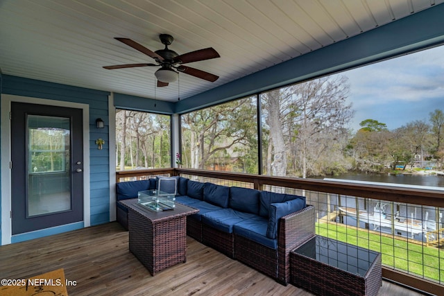 sunroom featuring a ceiling fan and a water view