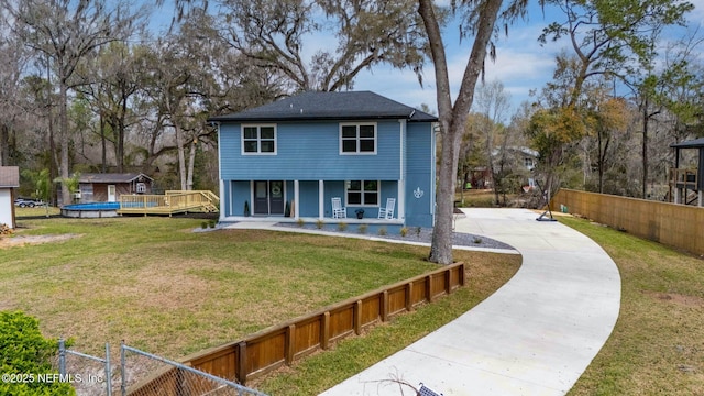 view of front facade with covered porch, a front yard, and fence