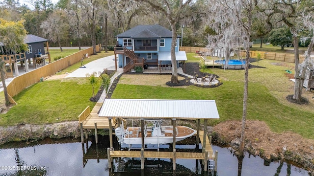 view of dock with boat lift, a fenced backyard, a water view, a yard, and stairway