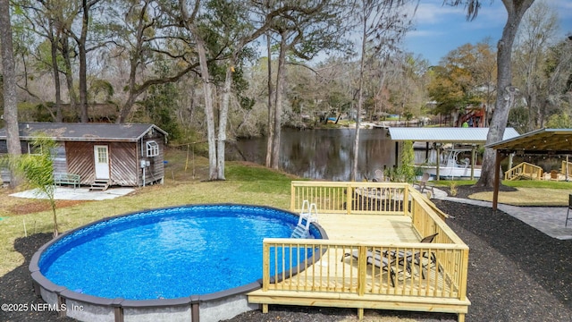 pool featuring a lawn, an outdoor structure, and a deck with water view