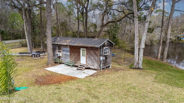 view of outbuilding featuring entry steps, a forest view, a water view, and an outbuilding