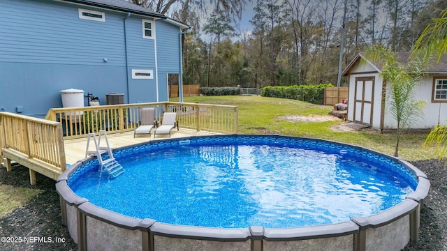 view of swimming pool featuring a fenced backyard, an outbuilding, a yard, a wooden deck, and a shed