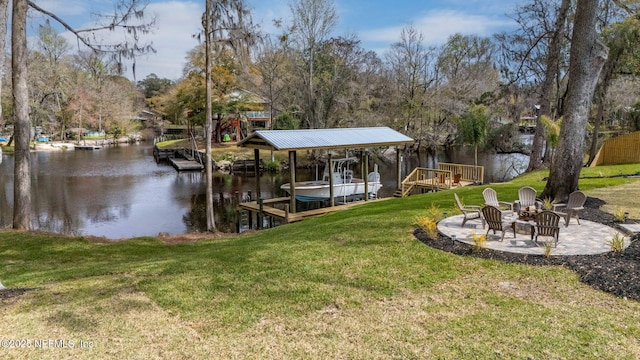 view of dock with boat lift, a fire pit, a water view, a yard, and a patio area