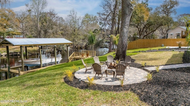 view of yard featuring a patio, boat lift, a water view, fence, and a boat dock