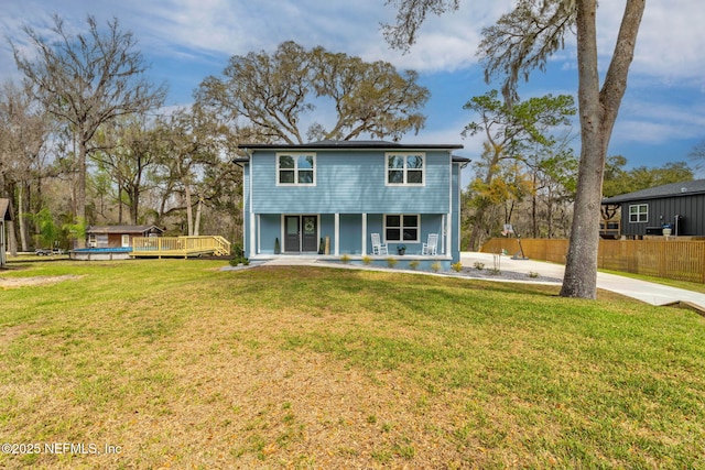 view of front facade with covered porch, fence, and a front lawn