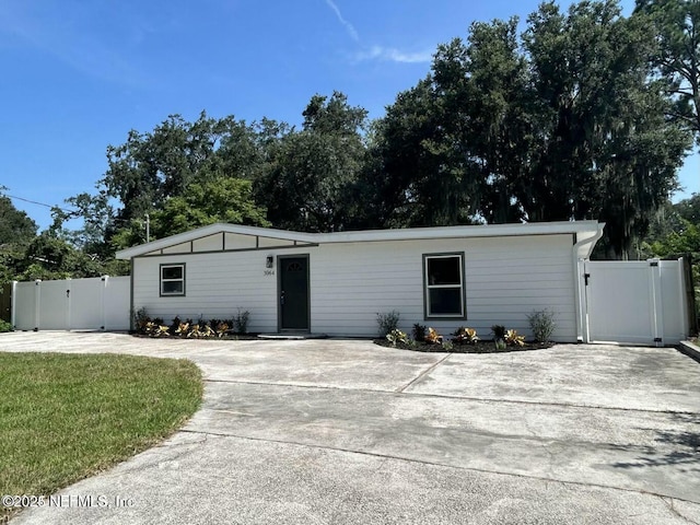 view of front of home featuring driveway, a front yard, fence, and a gate