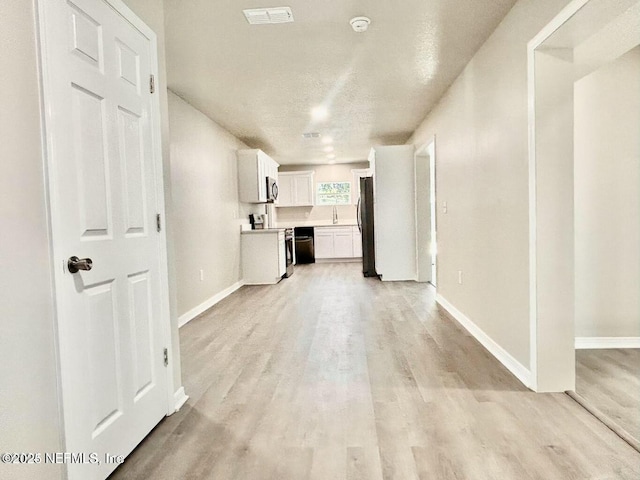 kitchen featuring light wood-style flooring, visible vents, baseboards, white cabinetry, and light countertops