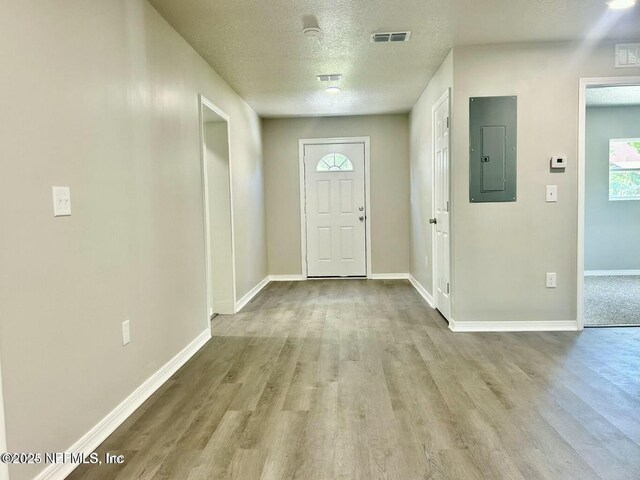 entryway featuring visible vents, a textured ceiling, wood finished floors, electric panel, and baseboards