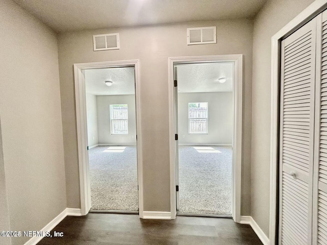 interior space featuring visible vents, a textured ceiling, and baseboards