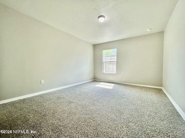 empty room with carpet flooring, a textured ceiling, and baseboards