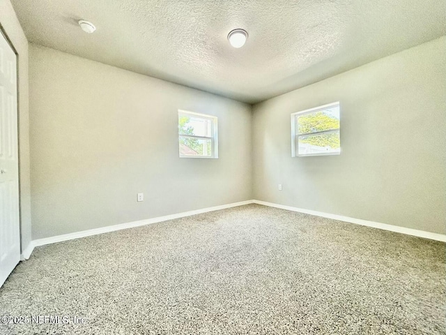 carpeted empty room with baseboards and a textured ceiling