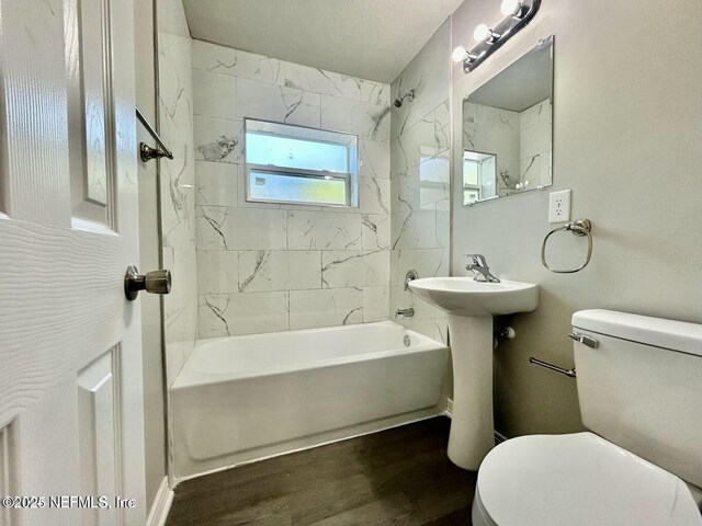 bathroom featuring a sink, shower / washtub combination, wood finished floors, and toilet