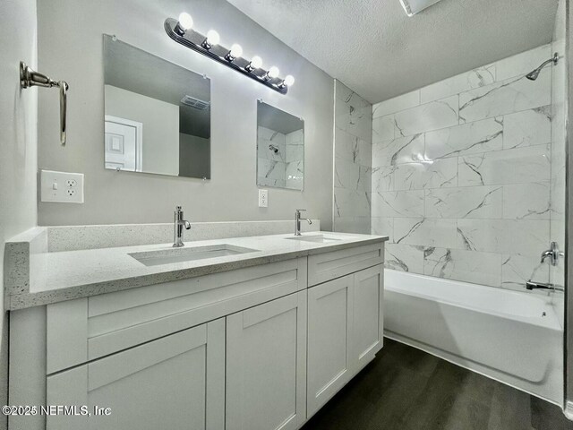 full bath with wood finished floors, a sink, a textured ceiling, and shower / bathtub combination