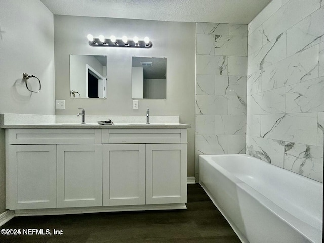 bathroom featuring double vanity, a textured ceiling, a sink, and wood finished floors